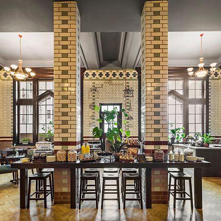 Kimpton Clocktower By Ihg Otel Manchester Dış mekan fotoğraf The photo shows a stylish dining area, likely a breakfast or buffet space within a hotel or restaurant. The interior features tall, elegant windows that allow natural light to fill the room, and the walls are adorned with intricate tiled designs, sho